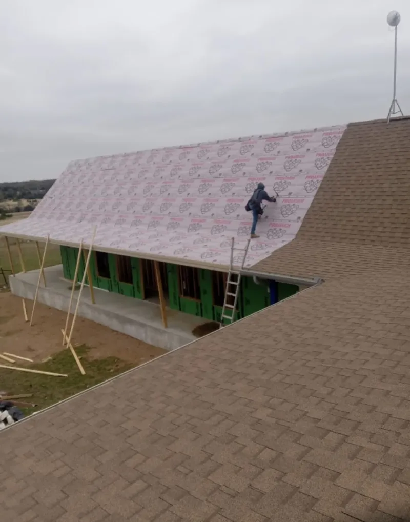 Worker preparing underlayment for a metal roof installation in Ensley